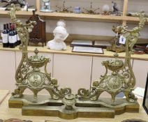A pair of French bronze chenets, 19th century, with ornate decoration and cherub cartouche,