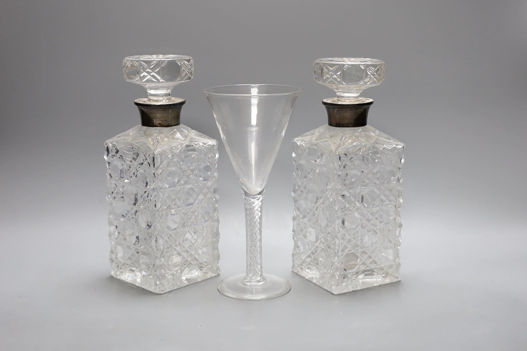 A pair of silver mounted cut glass decanters and stoppers and an air twist stemmed goblet,