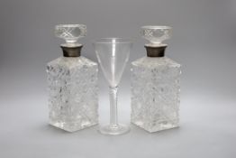A pair of silver mounted cut glass decanters and stoppers and an air twist stemmed goblet,