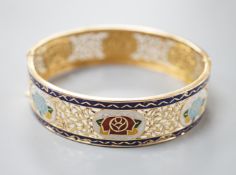 A pierced yellow metal and polychrome enamel set hinged bangle, gross weight 25.3 grams, (enamel a.