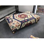 A large rectangular coffee table / footstool with antique kelim upholstery on stained turned beech