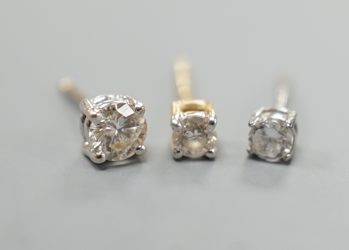 Two odd diamond set ear studs, the stones of various sizes and one paste set ear stud, gross