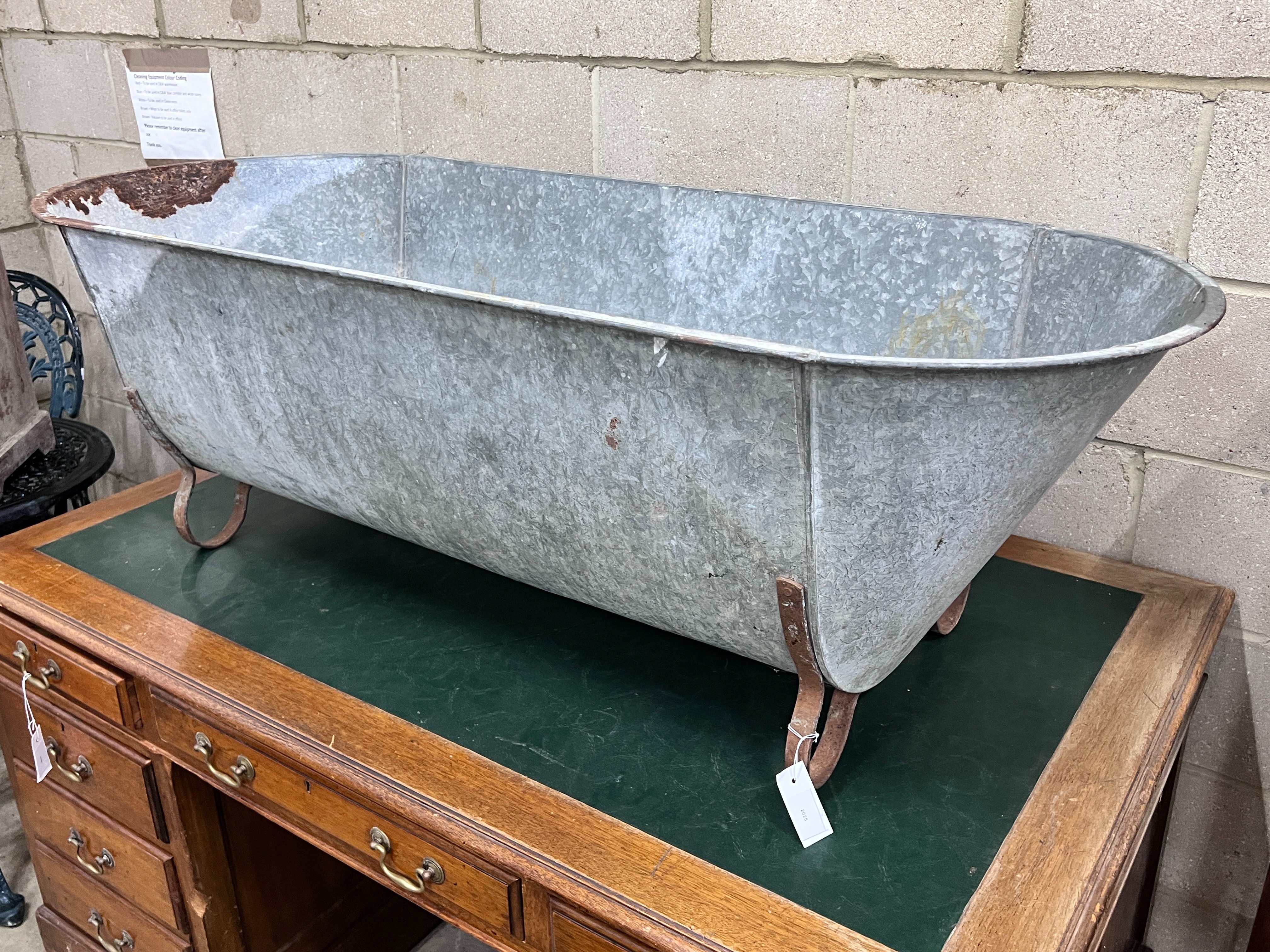 A vintage galvanised trough on wrought iron feet, length 146cm, depth 62cm, height 49cm