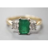 A modern 18ct gold, emerald and diamond set three stone ring, size N, gross weight 3.5 grams.