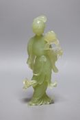 A Chinese carved bowenite figure of a lady holding a floral sprig, 21cm tall