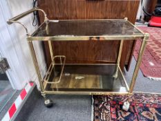 A French gilt metal smoked glass two tier trolley, width 74cm, depth 40cm, height 70cm