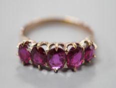 An early 20th century yellow metal and graduated five stone ruby set half hoop ring, size O, gross