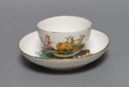 A Meissen teacup and saucer painted with a landscape with children in robes with recumbent sheep,