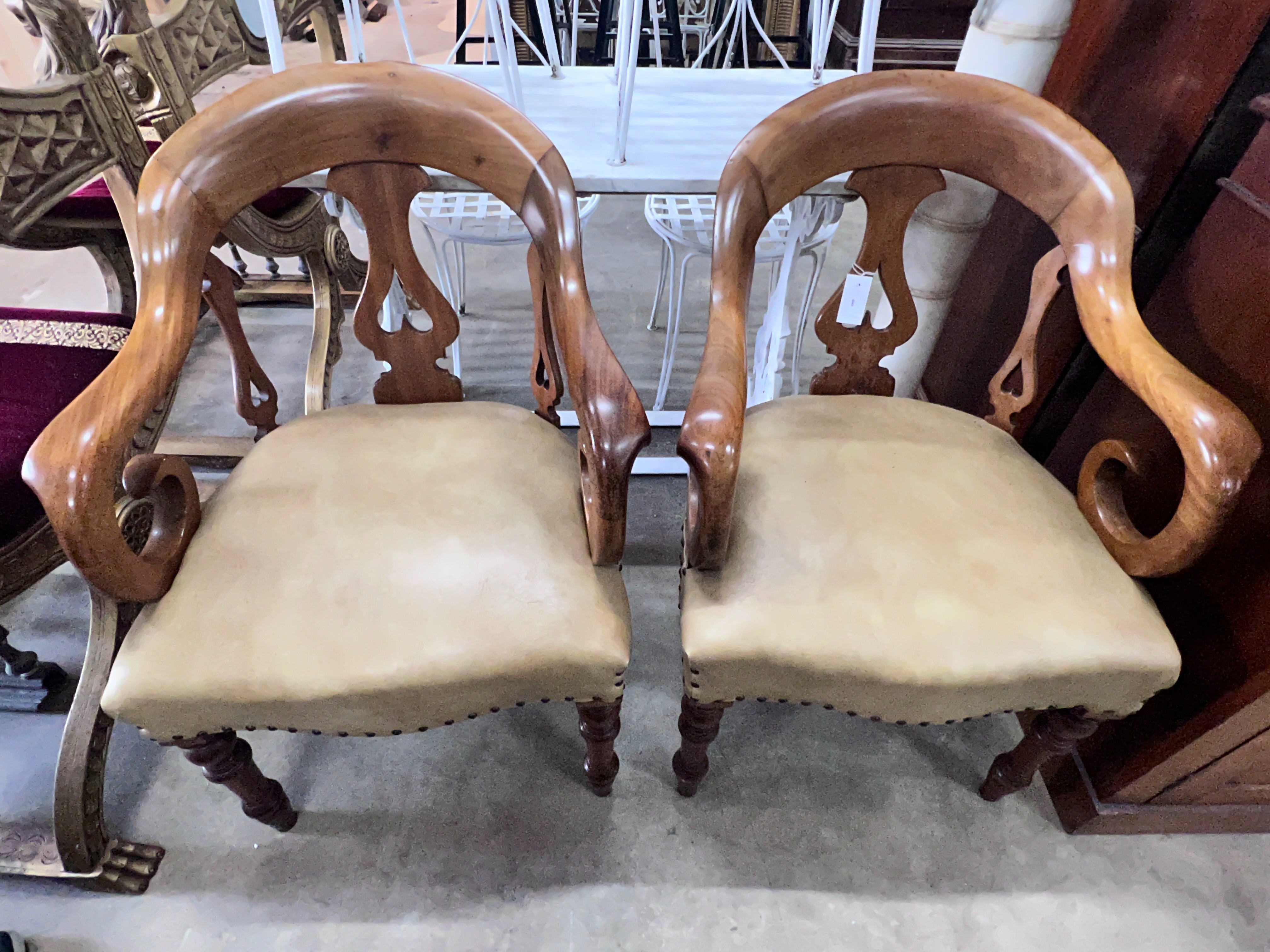 A pair of Victorian walnut elbow chairs with light brown leather seats, width 59cm, depth 51cm,