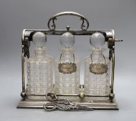 A Victorian electroplate three bottled tantalus, with a silver whisky and gin label plus pair of