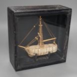 A cased bone Napoleonic style, carved prisoner-of-war ship, 18cms wide x 18.5cms high