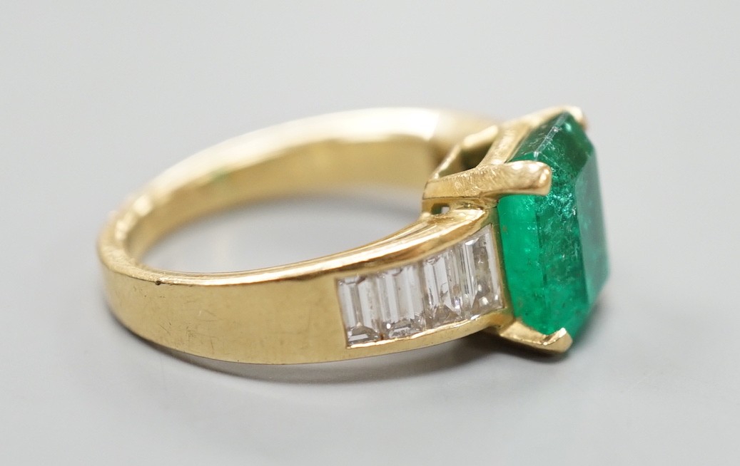 A modern yellow metal and single stone emerald set dress ring, with graduated baguette cut diamond - Image 3 of 4