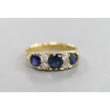 A late Victorian 18ct gold, three stone sapphire, and four stone diamond set half hoop ring, with