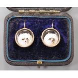 A cased pair of yellow metal and circular enamel earrings, decorated with the heads of a dog,