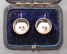 A cased pair of yellow metal and circular enamel earrings, decorated with the heads of a dog,