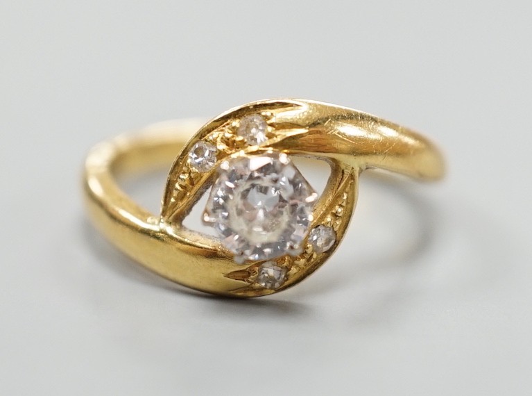 A continental yellow metal and single stone diamond set ring, with diamond set crossover