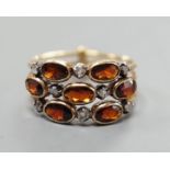 A late Victorian yellow metal, garnet and diamond chip cluster set triple shank ring, size M,