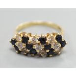 A modern 18ct, sapphire and diamond cluster set seven row half hoop ring, size P, gross weight 5.4