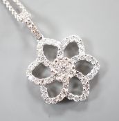 A modern 750 white metal and diamond chip set openwork flower head cluster pendant, overall 24mm, on