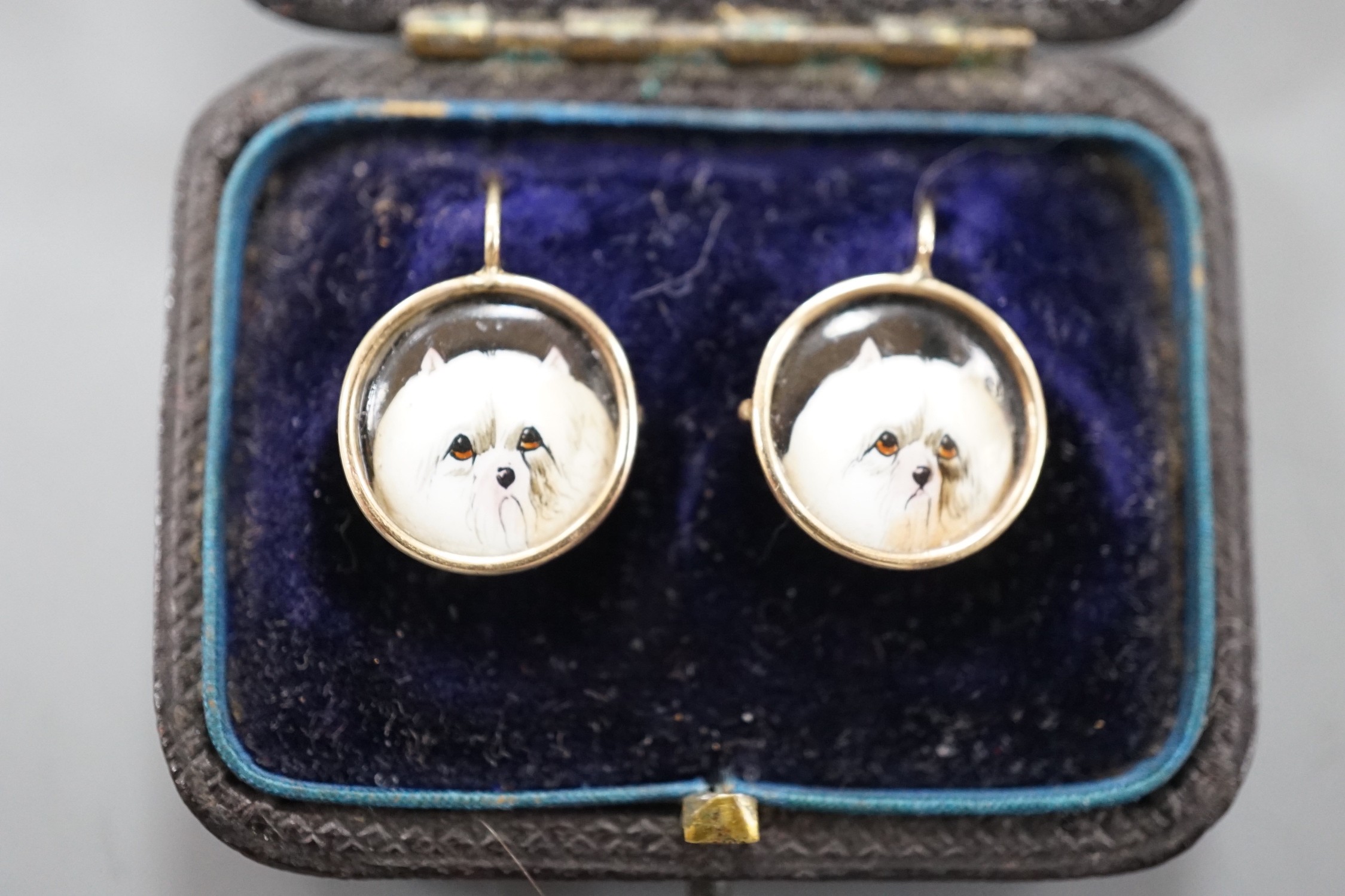 A cased pair of yellow metal and circular enamel earrings, decorated with the heads of a dog, - Image 2 of 4
