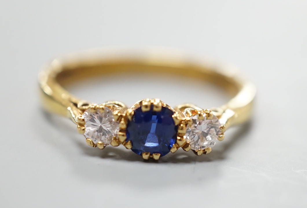 A modern 18ct gold, sapphire and diamond set three stone ring, size S, gross weight 4.4 grams, the