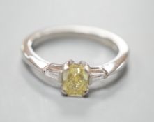 A modern platinum and single stone fancy yellow diamond set ring, with trapeze cut diamond set
