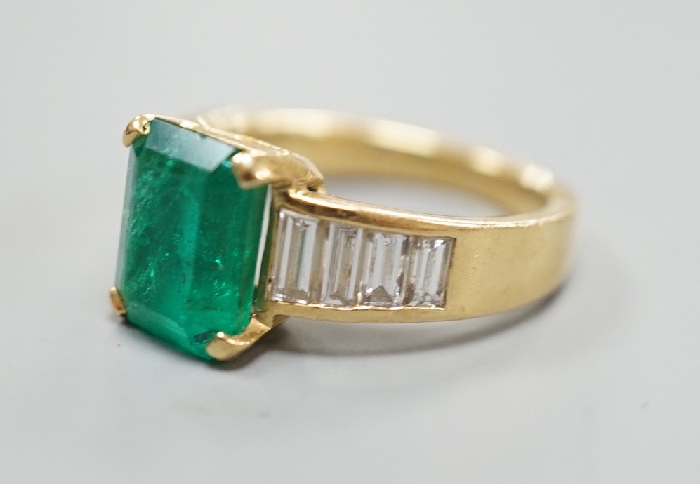 A modern yellow metal and single stone emerald set dress ring, with graduated baguette cut diamond - Image 2 of 4