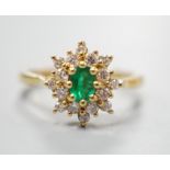 A modern 18ct gold, emerald and diamond set star shaped cluster ring, size L/M, gross weight 3.8