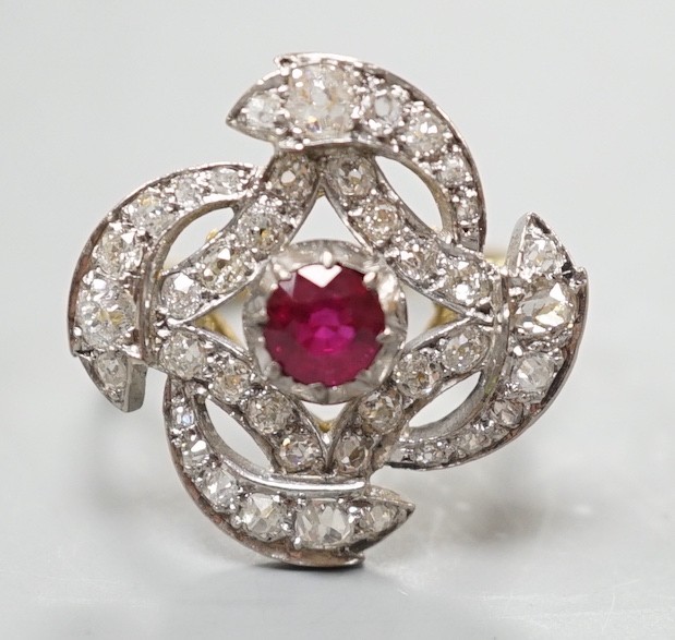 A yellow metal, ruby and diamond cluster set dress ring, in a pierced scroll setting, size O,