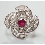 A yellow metal, ruby and diamond cluster set dress ring, in a pierced scroll setting, size O,