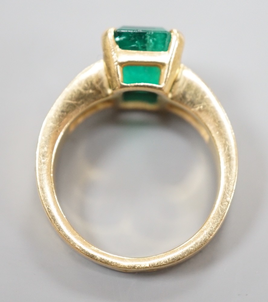 A modern yellow metal and single stone emerald set dress ring, with graduated baguette cut diamond - Image 4 of 4