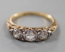 An early 20th century yellow metal and graduated three stone diamond ring, with diamond chip set