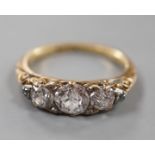 An early 20th century yellow metal and graduated three stone diamond ring, with diamond chip set