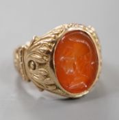 An early 20th century yellow metal and intaglio carnelian set signet ring, the matrix carved with