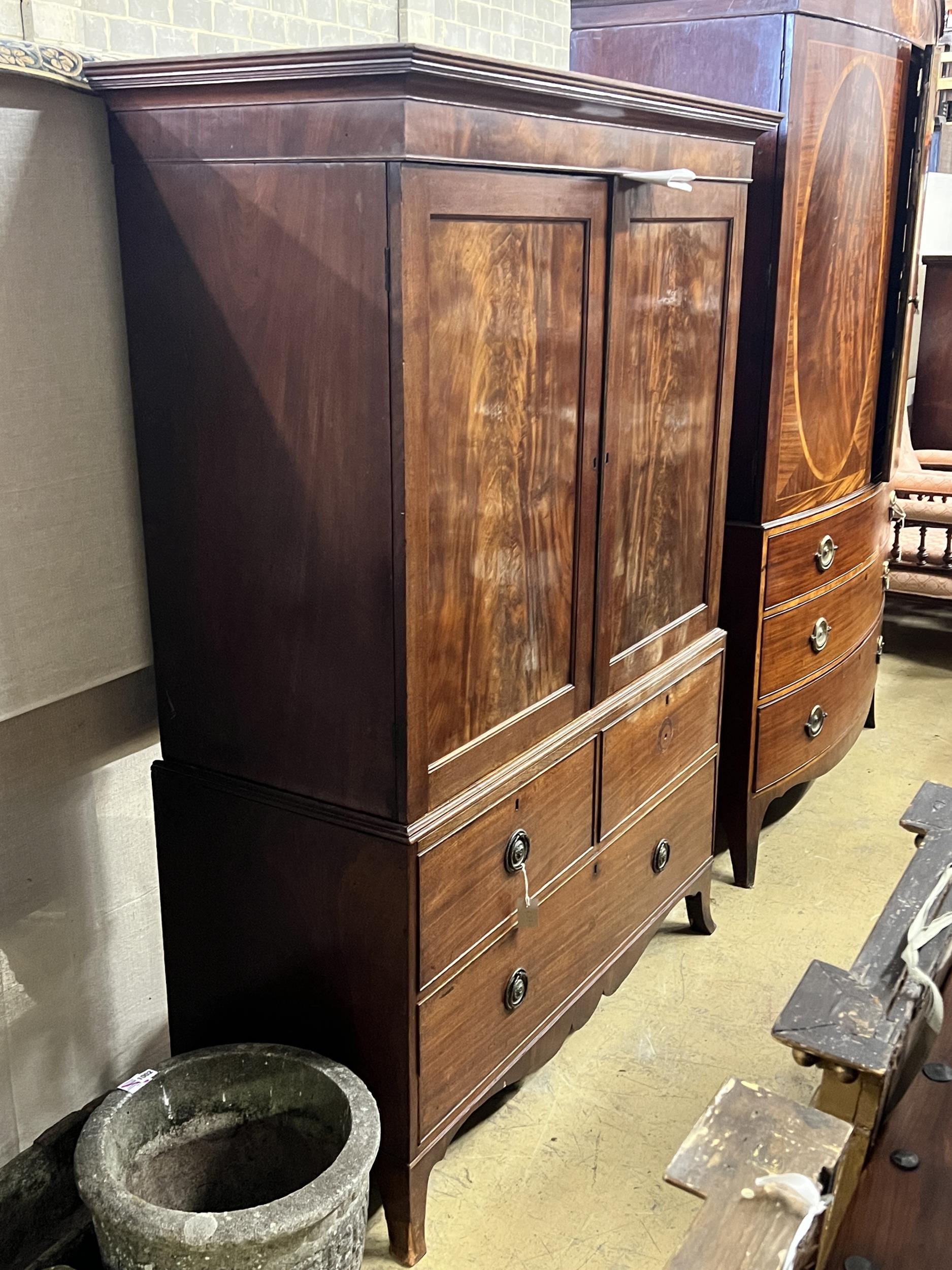 A George III mahogany linen press converted to a hanging wardrobe with part dummy drawer front,