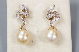 A modern pair of yellow metal, cultured pearl and diamond set scroll drop drop earrings, overall