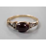 A 19th century yellow metal and single stone cabochon garnet set ring, with diamond chip set