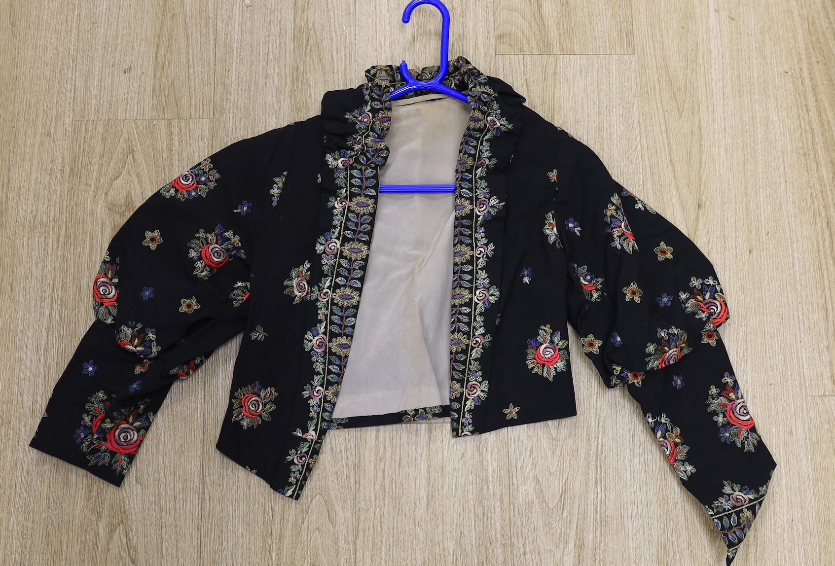 A 1930's-40's black evening jacket, embroidered with multi coloured floral embroidery, together with