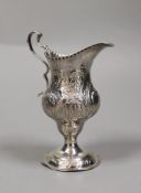 A George III silver inverted pear shaped cream jug, with later embossed decoration, Stephen Adams I,