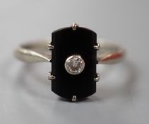 A 9ct white metal, black onyx and single stone diamond set tablet ring, size O, gross weight 2.1