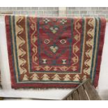 A Kilim runner with geometric motifs on a red ground, 394 x 96cm