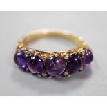 A late Victorian yellow metal and five stone graduated cabochon amethyst set half hoop ring, with
