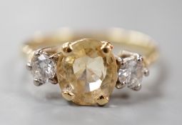 A yellow metal, singe stone oval cut yellow sapphire and two stone round cut diamond set ring,