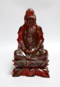A Chinese ‘cherry amber’ phenolic seated figure of Guanyin, 29cms high,
