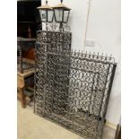 A pair of black painted wrought iron scroll work gates with matching lantern posts, total width