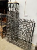 A pair of black painted wrought iron scroll work gates with matching lantern posts, total width