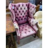 A George III style button back wing armchair upholstered in faded burgundy buttoned leather, width