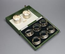 A cased set of six modern silver napkin rings and one other pair of engine turned silver napkin