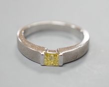A modern sandblasted platinum and solitaire rectangular cut fancy yellow diamond set ring, size M/N,