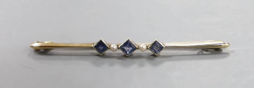 An Edwardian 15ct, three stone sapphire and two stone seed pearl set bar brooch, 57mm, gross 3.4